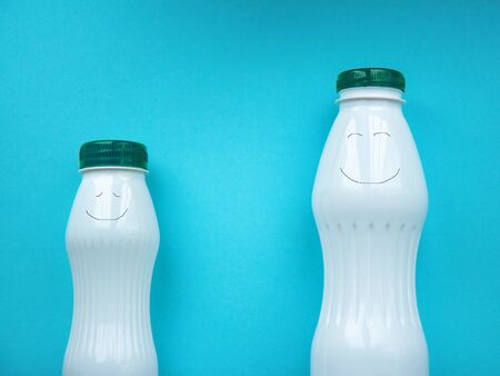 Two white bottle with green bottle cap on a blue background. With hand-drawn smiles. Front view