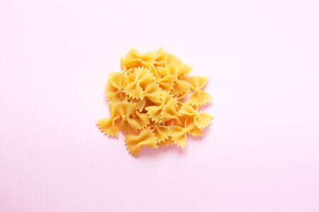 Raw farfalle pasta isolated on pink background. Selective focusの写真素材