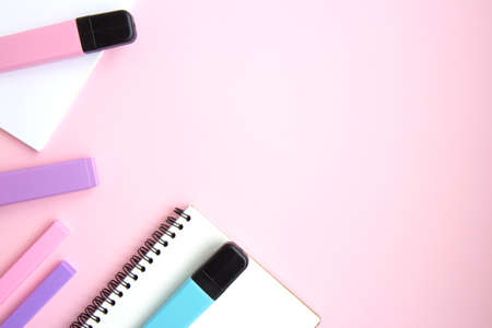 White open notepad, colorful markers, eraser on pink background with space for text. School stationery and supplies. Back to school, creative workspace. Minimalistic set of colorful stationeryの写真素材