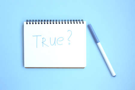 Open white notebook on a spiral on a bright blue background. Notepad with caption: true. Stationery on a blue background with space for text. Minimalism. Flat layの写真素材