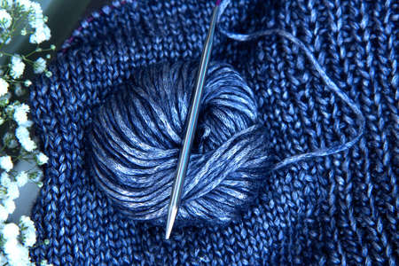 Needlework and a bouquet of white flowers. Texture beautiful knitted blue fabric with metallic...