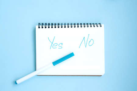 Open white notebook on a spiral and marker on a bright blue background. Notepad with captions: affirmation and denial. Stationery on a blue background with space for text. Minimalism. Flat layの写真素材