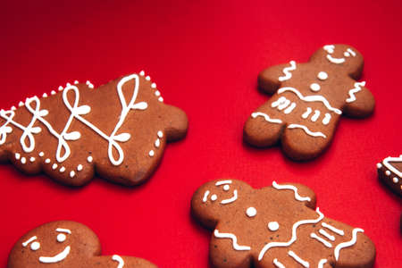 Tasty homemade Christmas gingerbread cookies of various shapes with sugar glaze on a bright festive red background. Merry Christmas card. Concept of celebrating new year. Christmas moodの写真素材