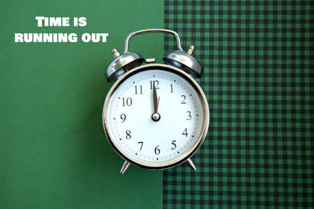 Beautiful vintage silver alarm clock on a green checkered background. Time concept. Holiday routine....