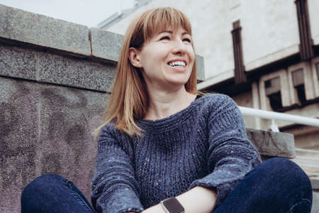 Smiling girl face. Young beautiful woman in a cozy blue sweater spends time outdoors. Lifestyle...