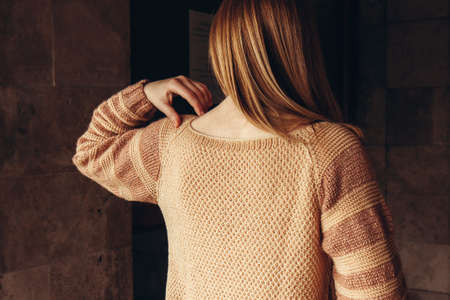 Young woman with red hair in a cozy beige sweater spends time outdoors. Lifestyle portrait of female