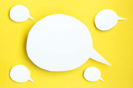 Some white paper speech bubbles concept. Cartoon speech with clipping path on bright yellow background with contrasting shadowの写真素材