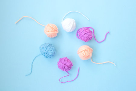 Several colorful skeins of thread are arranged in a circle on a light blue background with copy space. Close upの写真素材