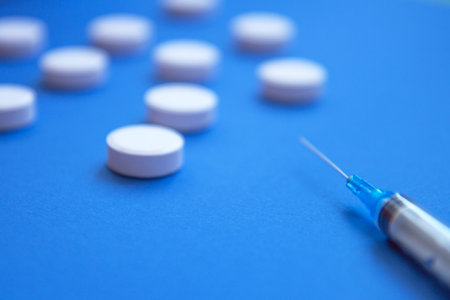 Set of white pills and syringe on blue background. Pills background. White tablets on a blue backgroundの写真素材