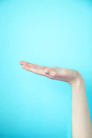 Close-up of beautiful young woman hand isolated on blue background. Palm upの写真素材