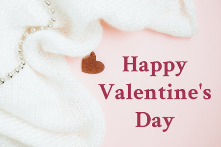 Valentines Day background. Red heart and folds white knitted fabric on pastel pink background. Valentines day concept. Flat lay with copy spaceの写真素材