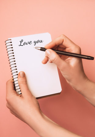 Woman's hand holding pen and open spiral notebook with the inscription I love you on light background. Planning conceptの写真素材