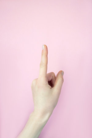 Female hand isolated on pink background. Number one index finger on backgroundの写真素材