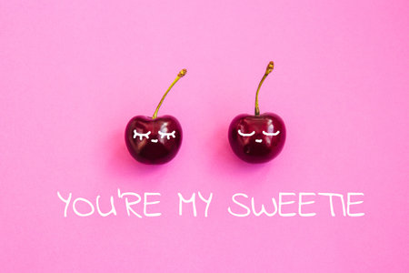 Two ripe cherries on a light pink background. Valentine's Day concept. Inscription you're my sweetie