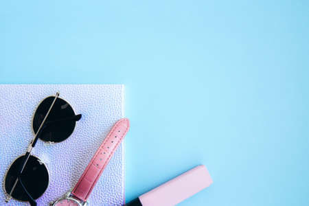 Notebook and sunglasses, wristwatch, marker on a bright blue background with space for text. Creative workspace. Flat layの写真素材