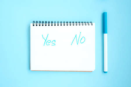 Open notebook with white blank pages on blue background. Notepad with an inscription: Yes No. Stationery on a blue background with space for text. Minimalism. Flat layの写真素材