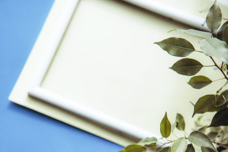 Portrait empty white wooden frame mockup on blue background and a green indoor plant in a potの写真素材