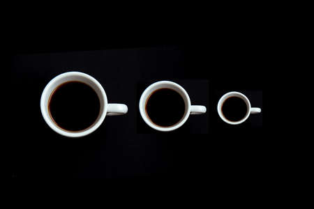 Three cups of black coffee. Coffee in a white cup isolated on black background. Selective focus....