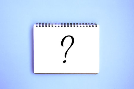Open notebook with white blank pages on blue background. Notepad with a drawn question mark....