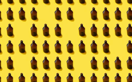 Empty brown medicine glass bottle of cosmetic liquid on bright yellow background. Concept of the organic, zero waste cosmetics. Pattern seamlessの写真素材