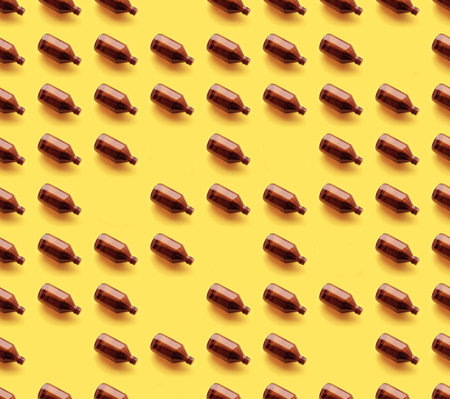 Empty brown medicine glass bottle of cosmetic liquid on bright yellow background. Concept of the organic, zero waste cosmetics. Pattern seamlessの写真素材