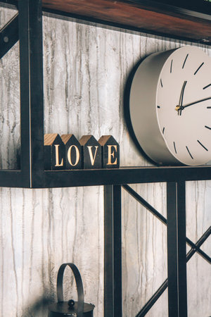 Shabby chic interior decor. White round clock and wooden letters on a vintage shelf. Word love made from wooden cubes. Home space decorationの写真素材