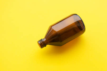 Empty brown medicine glass bottle of cosmetic liquid on bright yellow background. Concept of the organic, zero waste cosmeticsの写真素材