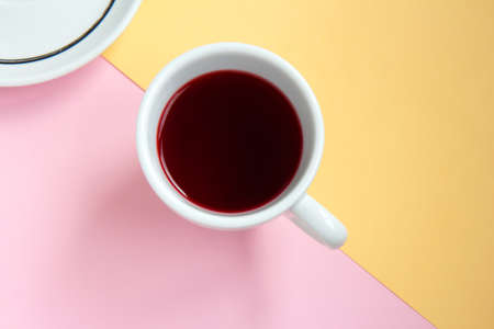 Hibiscus red tea in a white cup and saucer on pink and orange background divided on two parts. Selective focus. Top viewの写真素材