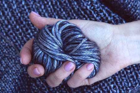 Needlework. Texture beautiful knitted bright violet fabric and clew as background. Woman's hand holding a clew. Female hobby conceptの写真素材