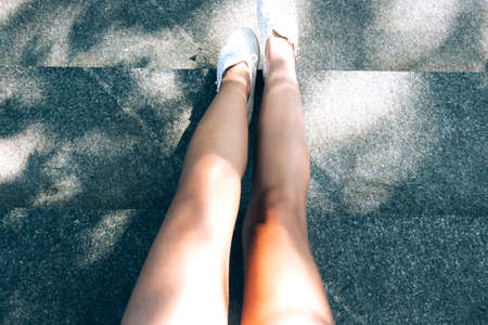 Slender naked female tanned legs top view on the stairs. Body in the rays of the sunの写真素材