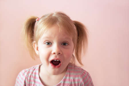 Beautiful little girl with a surprised face on a light background