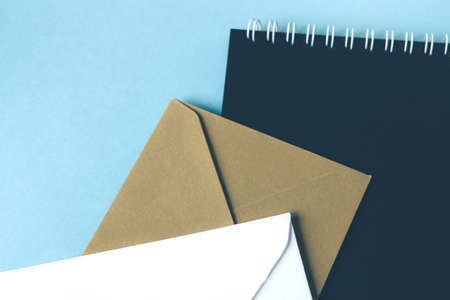 White and beige envelopes and notebook with black paper on blue background. Blank templateの写真素材