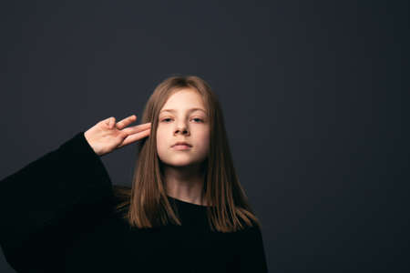 Beautiful brooding girl put her fingers to head on a dark backgroundの写真素材
