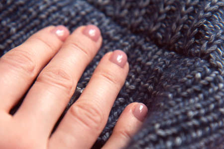 Needlework. Texture beautiful knitted blue fabric as background. Female hand on knitting. Female...