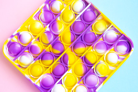 Trend bright multicolored antistress toy Pop it. Poppit new fidget toy on empty pink and blue background. Close upの写真素材