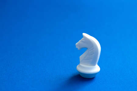 One chess knight on bright blue background. Abstract background. White chess figures for the game...