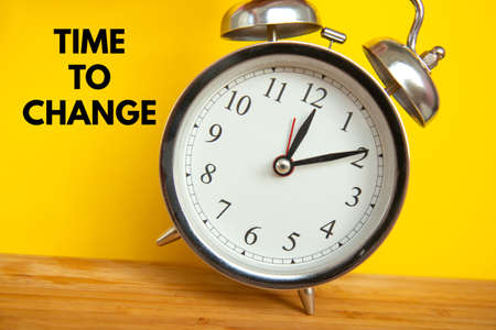 Retro alarm clock on bright yellow background with an inscription Time to change. Time conceptの写真素材