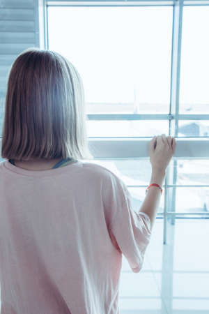 Teenage girl at the airport looking through the airport gate windows in planes