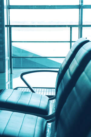 Empty waiting room with chairs at the modern airport on the background of airport gate windowsの写真素材