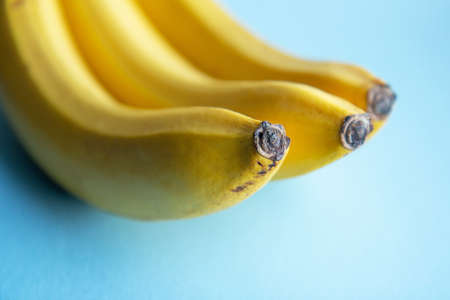 Ripe yellow bananas on a bright blue background. Close upの写真素材