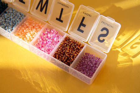 Transparent container for beads. Shiny multicolored seeds on a gold background. Multicolored set of...
