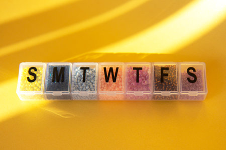 Transparent container for beads. Shiny multicolored beads on a gold backgroundの写真素材