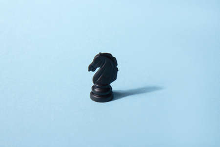 Black chess knight on a blue background. abstract background. Chess piece. Concept of leadership, lonelinessの写真素材