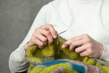 Young woman knitting warm sweater at homeの写真素材