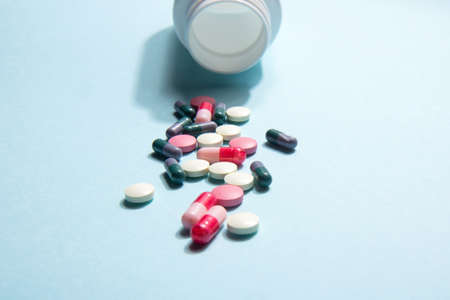 White bottle of vitamin tablets and capsules on a blue background. dietary supplements. Complementary and medical productsの写真素材
