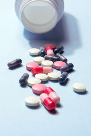 White bottle of vitamin tablets and capsules on a blue background. Dietary supplementsの写真素材