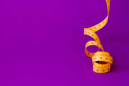 Bright yellow measuring tape a violet backgroundの写真素材