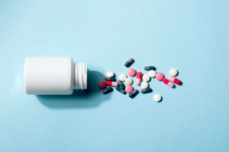 White bottle of vitamin tablets and capsules on a blue backgroundの写真素材