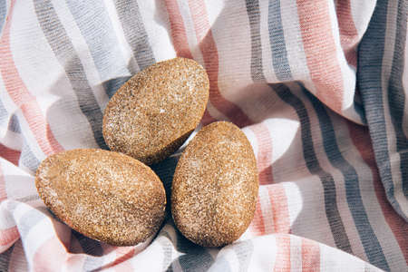 Easter holiday concept with golden eggs on the background of textilesの写真素材