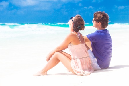 couple in love sitting in blue beach on vacation travelの写真素材